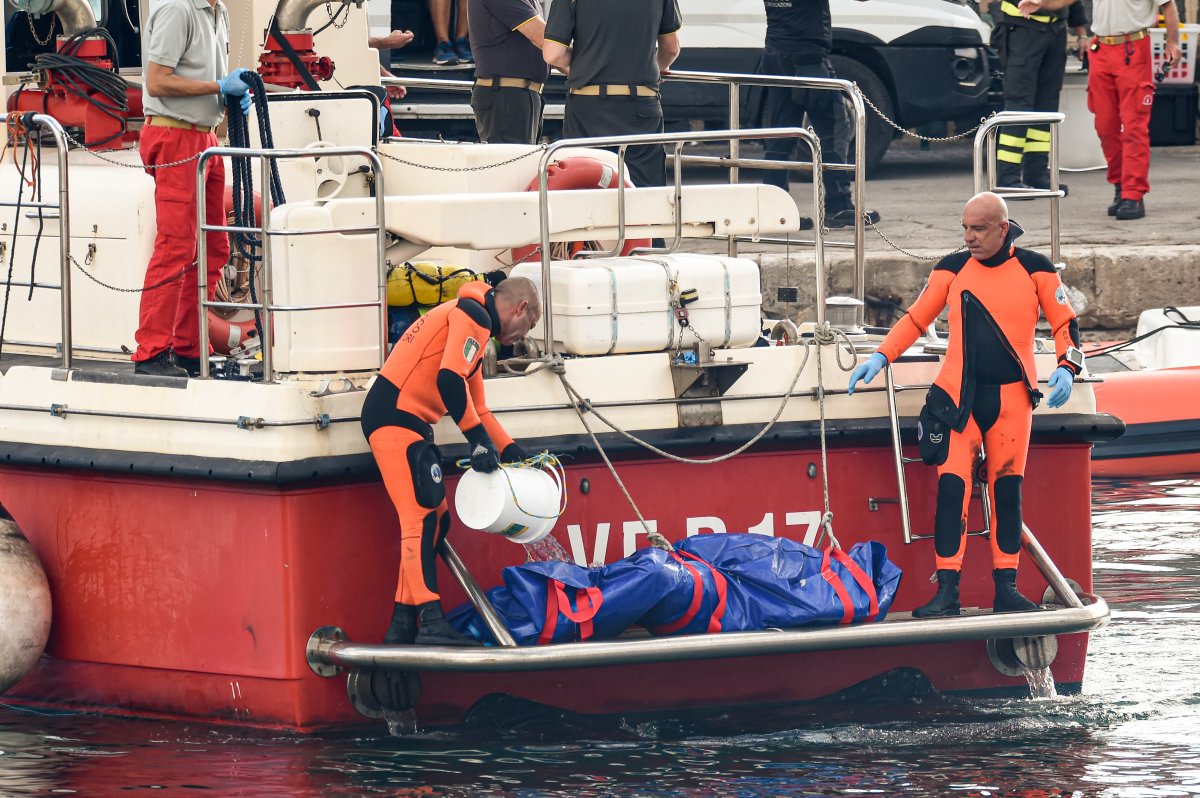 Italian firefighter divers bring ashore a blue plastic body bag containing one of the victims of the superyacht shipwreck.